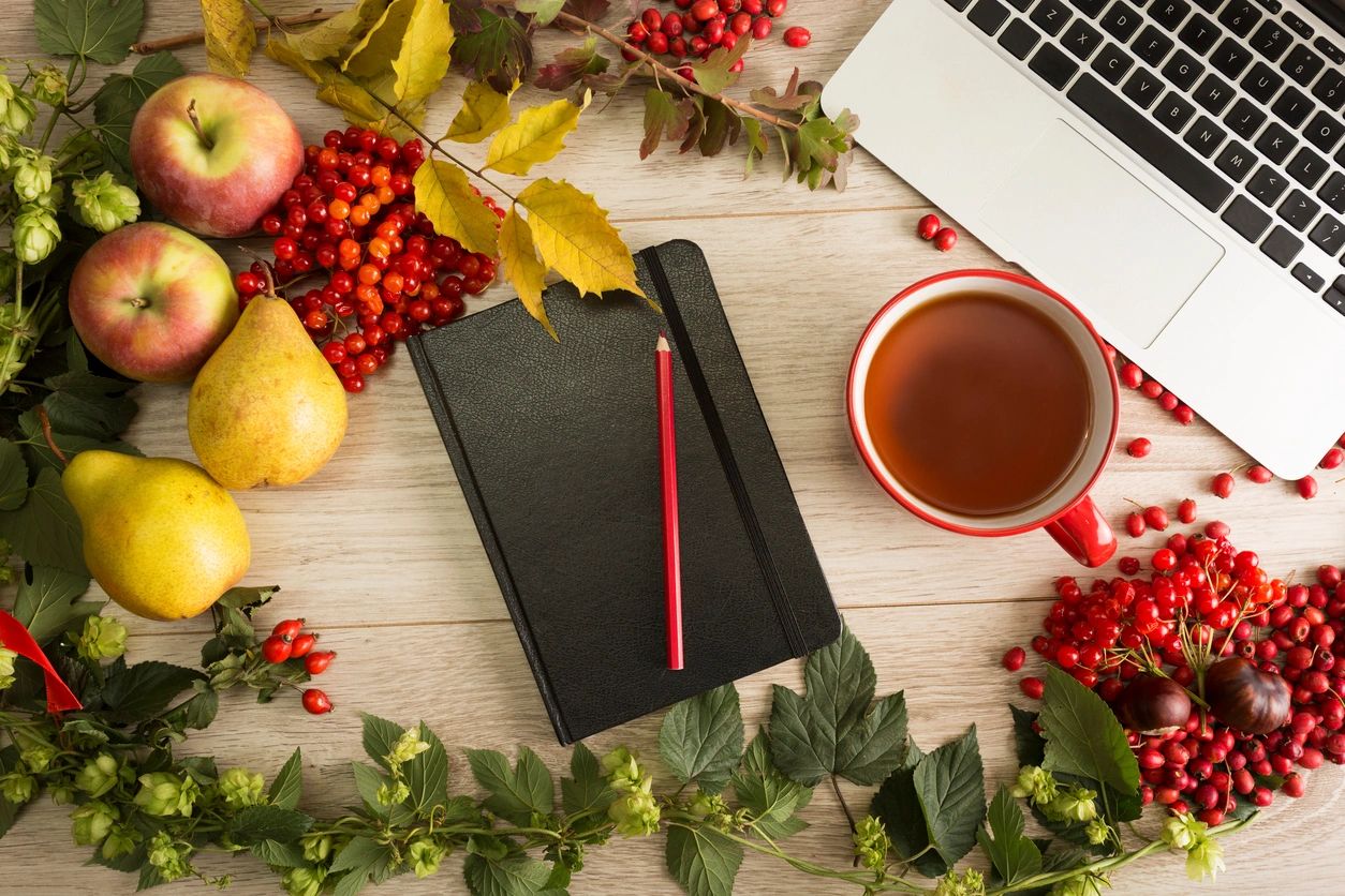 Decorative image for the blog on 5 key DRTV trends this 2024 holiday season. The image shows a festive table. On the table there is a notebook, a coffee cup and laptop.